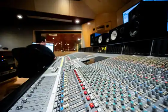 Audio engineer at a mixing console inside a professional recording studio control room