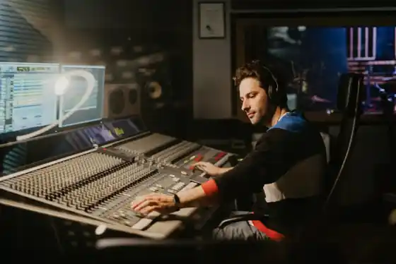 Audio engineer at a mixing console in a professional music studio control room