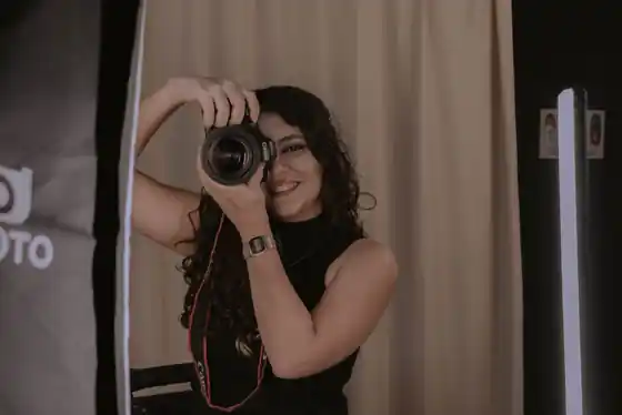 Person posing in a self photo studio with a neutral backdrop and ring light