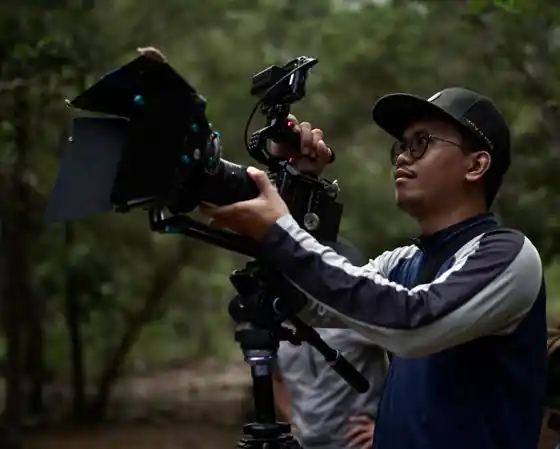 Videographer filming with a cinema camera against a Bali rice terrace backdrop